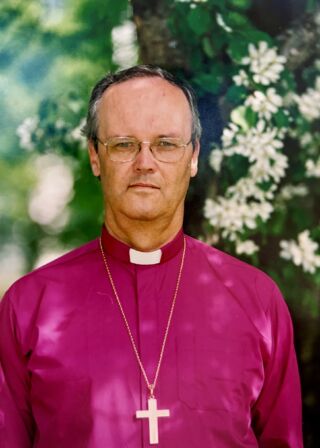Piispa Jorma Laulaja seisoo virkavuosinaan kesäisessä puutarhassa.